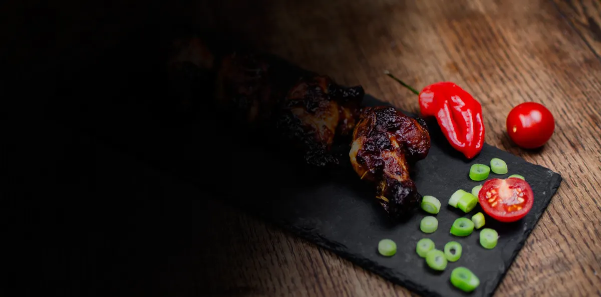 Glazed grilled chicken on a slate board with fresh chilli